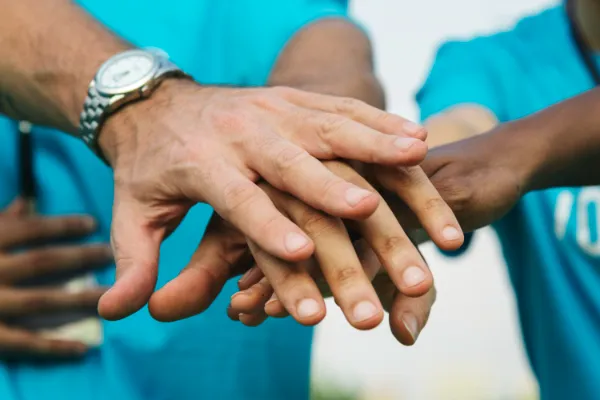 Team members joining hands in a spirit of collaboration